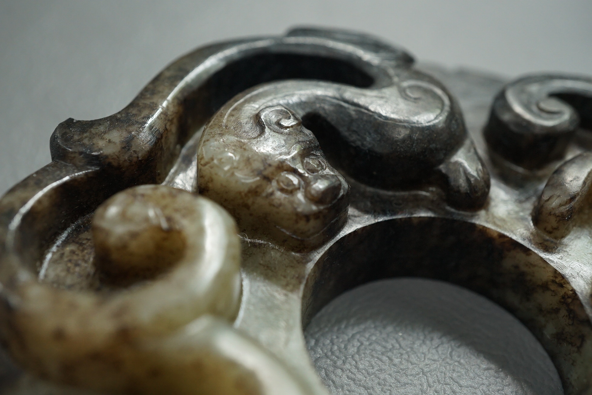 A Chinese pale celadon and black jade bi disc